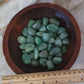 green aventurine tumble in a bowl with a ruler