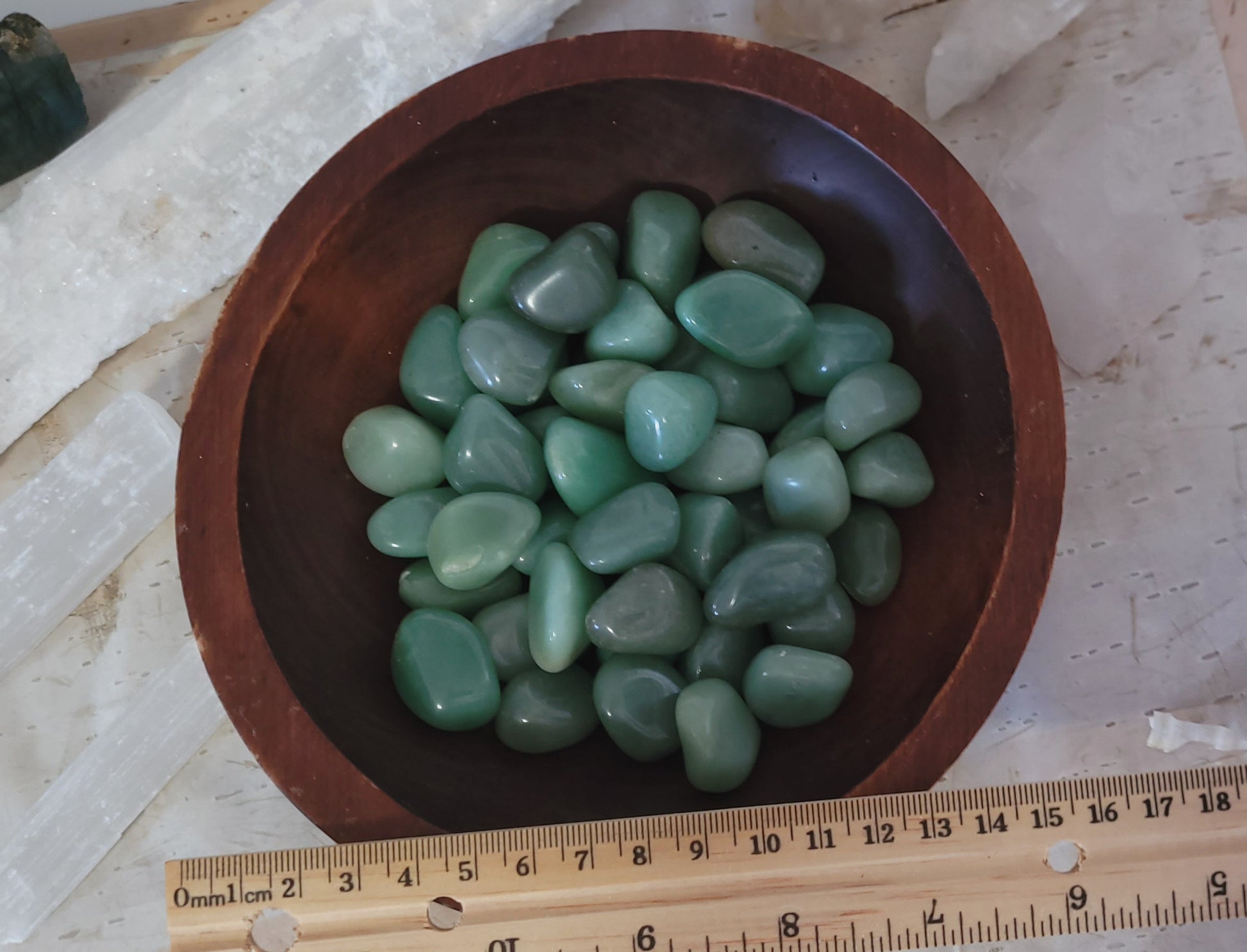 green aventurine tumble in a bowl with a ruler